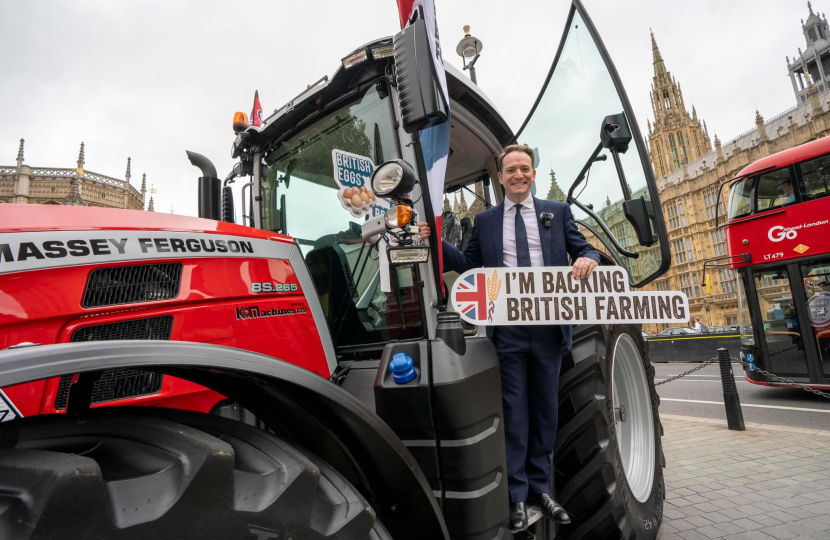 Gareth Davies MP on a tractor outside of the Palace of Westminster holding a sign reading "I'm backing British farming"