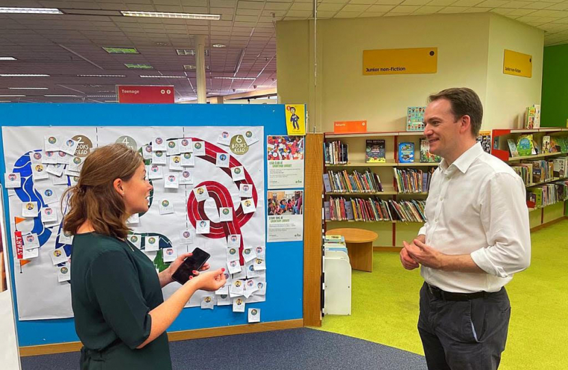 Gareth Davies MP with library staff in front of the summer reading challenge leader board